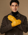 Yellow leather gloves on model, two gloves clasped at chest