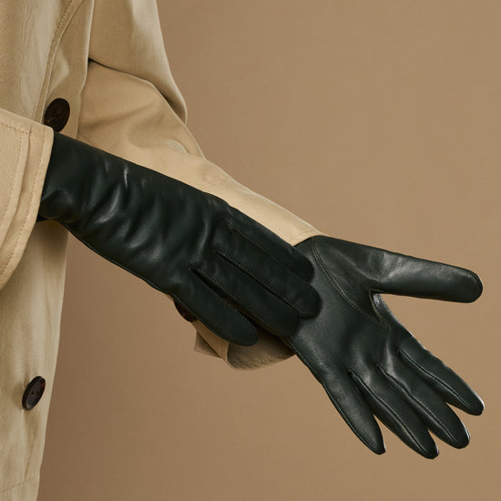 Dark green leather gloves laid out, showing long cuffs and finger seams