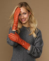 Orange leather gloves worn near face, long cuffs visible with finger stitching