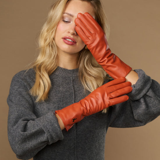 Orange leather gloves worn together; long cuff wraps along the forearm
