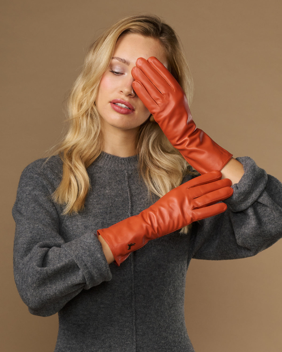 Orange leather gloves worn together; long cuff wraps along the forearm
