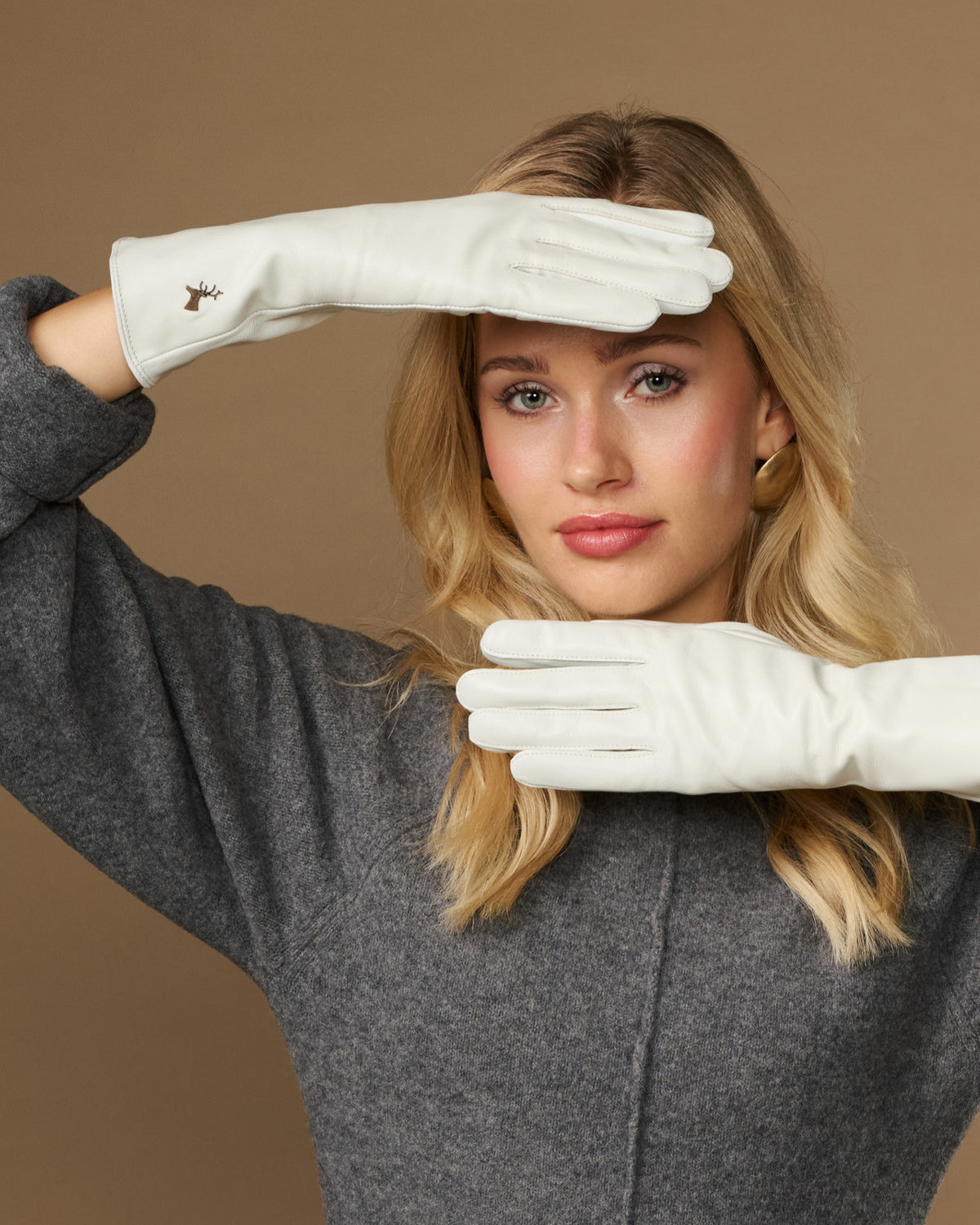 White long leather gloves with touchscreen fingertips, worn and posed across frame
