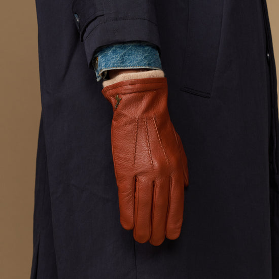 Cognac leather glove cuff with blue wool lining on dark sleeve