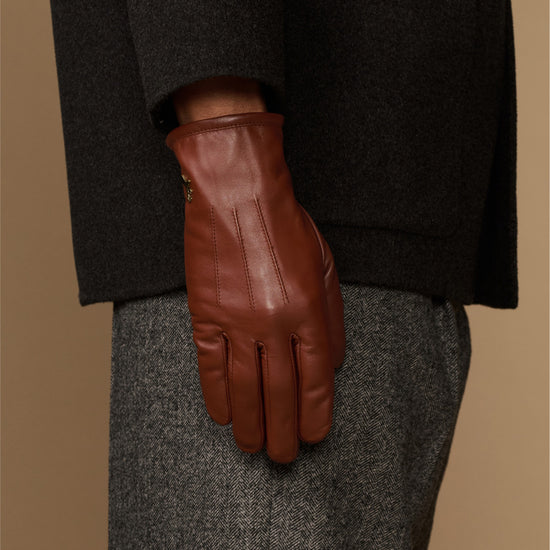 Cognac leather glove close-up with fleece-lined cuff and stitched finger panels