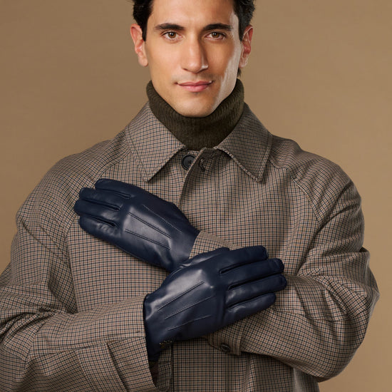 Navy leather gloves on a man’s hands, one glove held up across the other