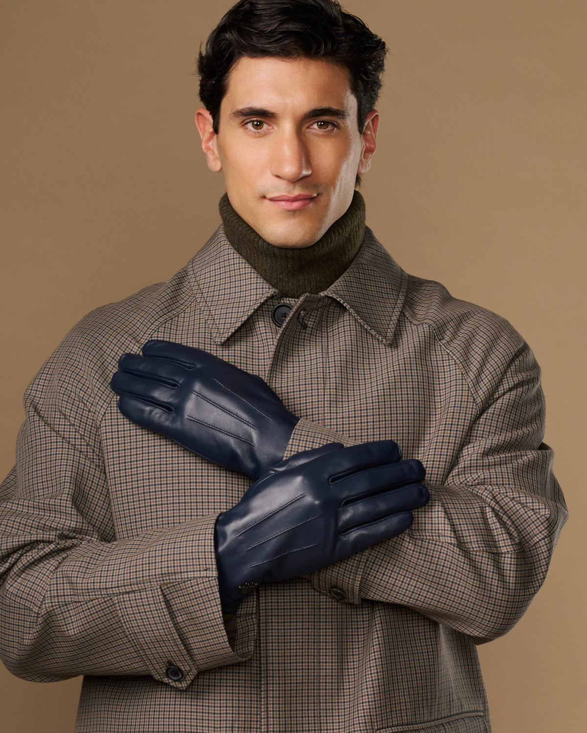 Navy leather gloves on a man’s hands, one glove held up across the other
