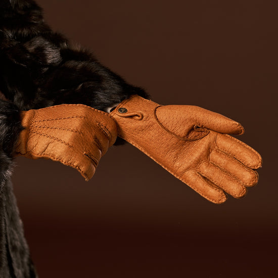 Cognac leather gloves in side view, stitched fingers and decorative cuff tab