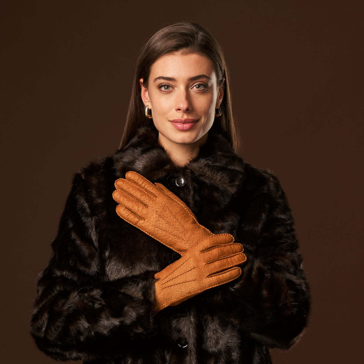 Cognac leather gloves worn by a woman, full hand coverage and short cuff