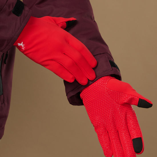 Red lightweight activity gloves showing textured grip palms and black touchscreen fingertips