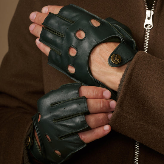 Close-up of dark green fingerless lambskin gloves with perforated fingers and adjustable wrist straps