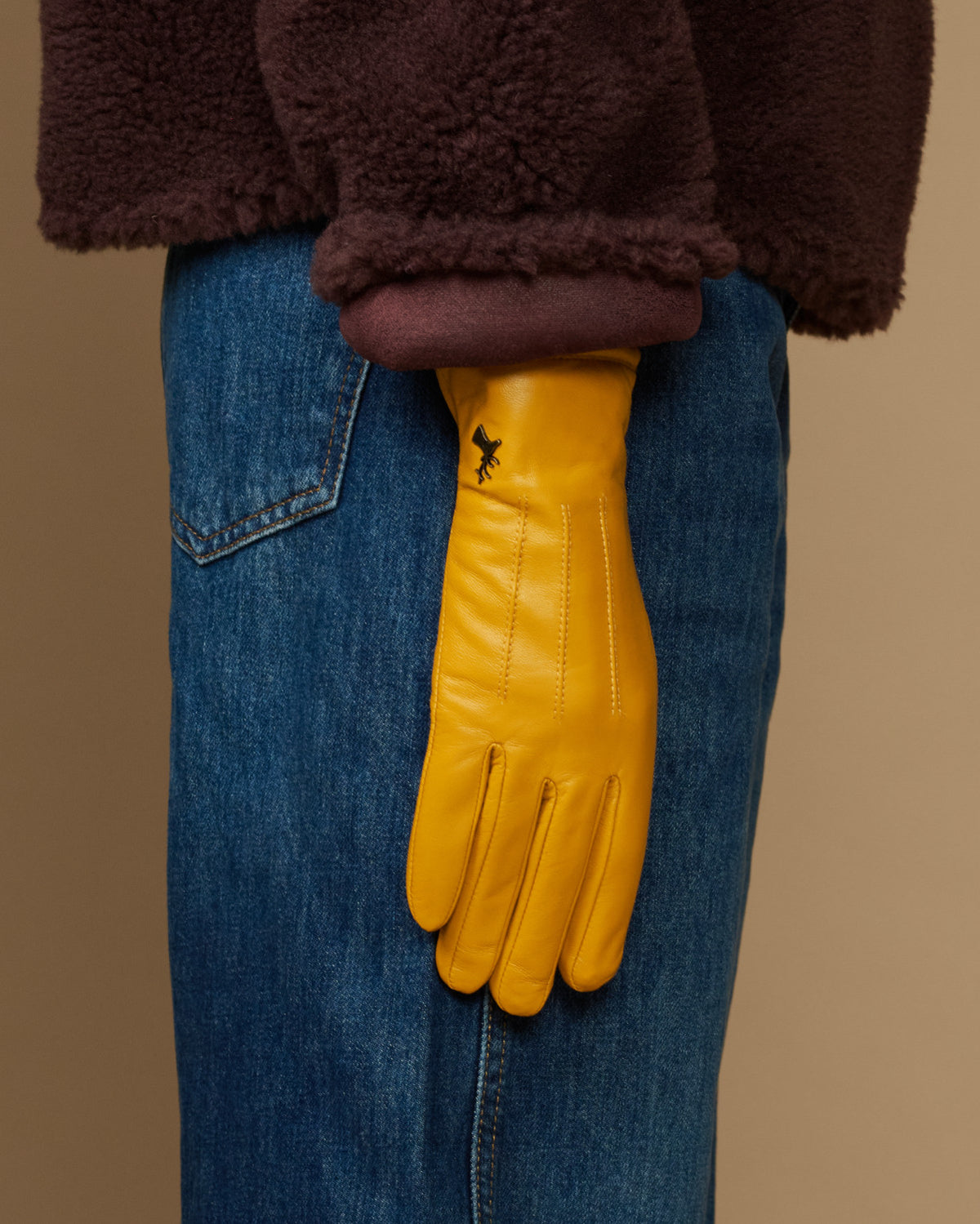 Yellow leather gloves with dark fleece cuff, shown over denim jeans