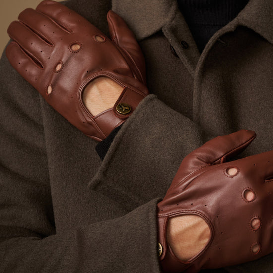 Brown leather driving gloves close-up with elastic wrist and touchscreen patch