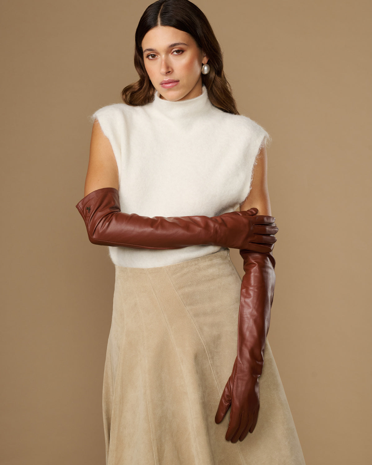 Chestnut brown leather opera gloves with long fit, one glove holding the other cuff