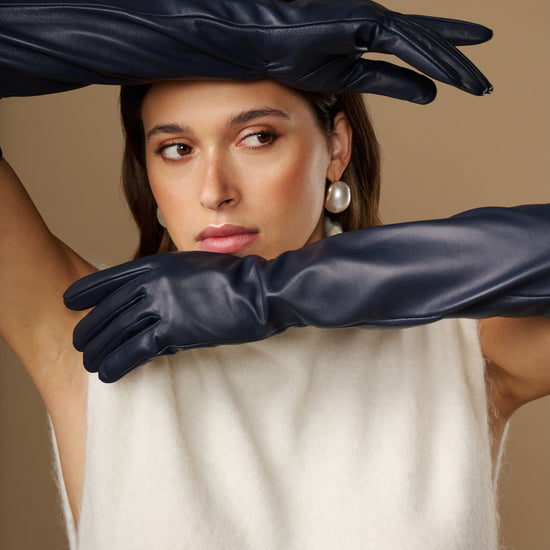 Navy leather opera gloves with long cuffs and silk lining, close-up with hands crossed
