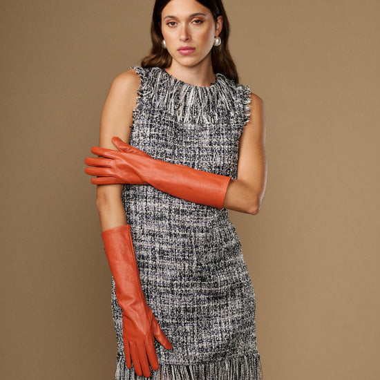 Women’s orange below-elbow leather gloves, one glove draped at side