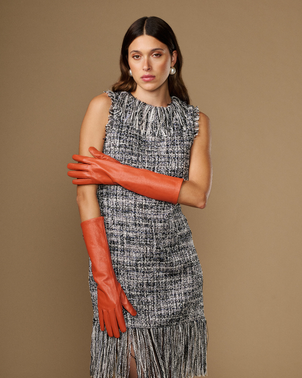 Women’s orange below-elbow leather gloves, one glove draped at side