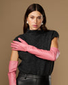 Women's pink leather gloves with long cuffs, arms crossed in front