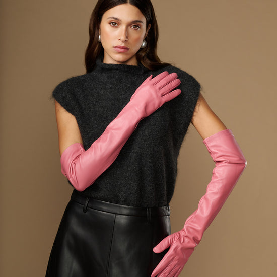 Women's pink leather gloves with long cuffs, hand posed near face
