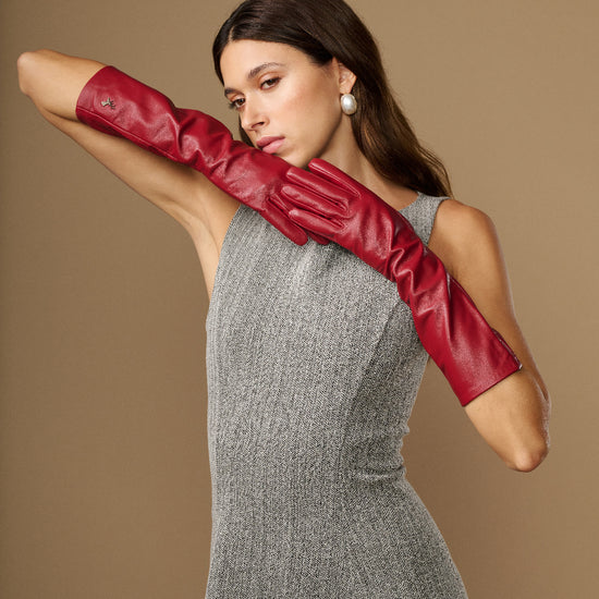 Single red leather glove extended across arm, highlighting below-elbow length and cuff