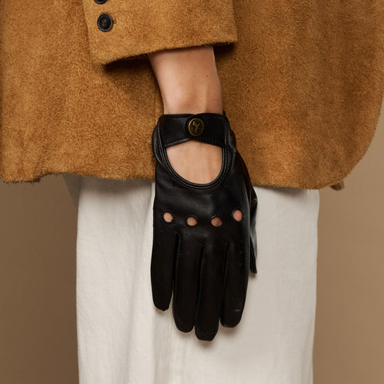 Black leather glove with oval emblem at wrist and studded finger panels.