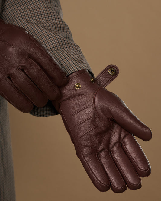 Brown leather glove close-up with press-stud at wrist and stitching detail